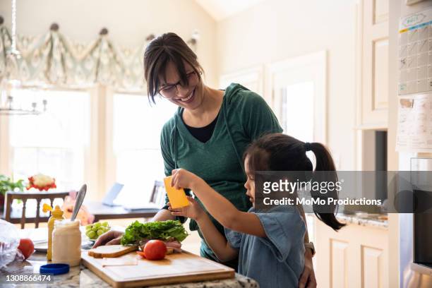 mother and daughter making sandwich in kitchen - chinese family taking photo at home stock-fotos und bilder