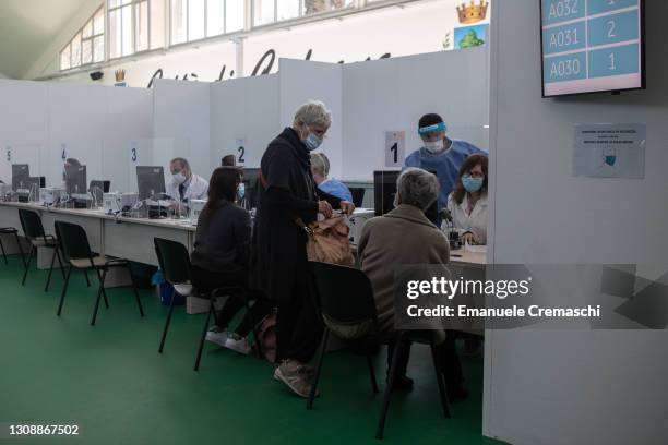 People sit while waiting for their turn to receive a dose of Pfizer Biontech vaccine at a sports center transformed into a vaccination hub on March...