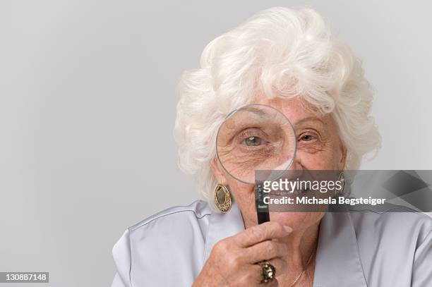 senior woman watching through a magnifying glass - gap closers stock pictures, royalty-free photos & images