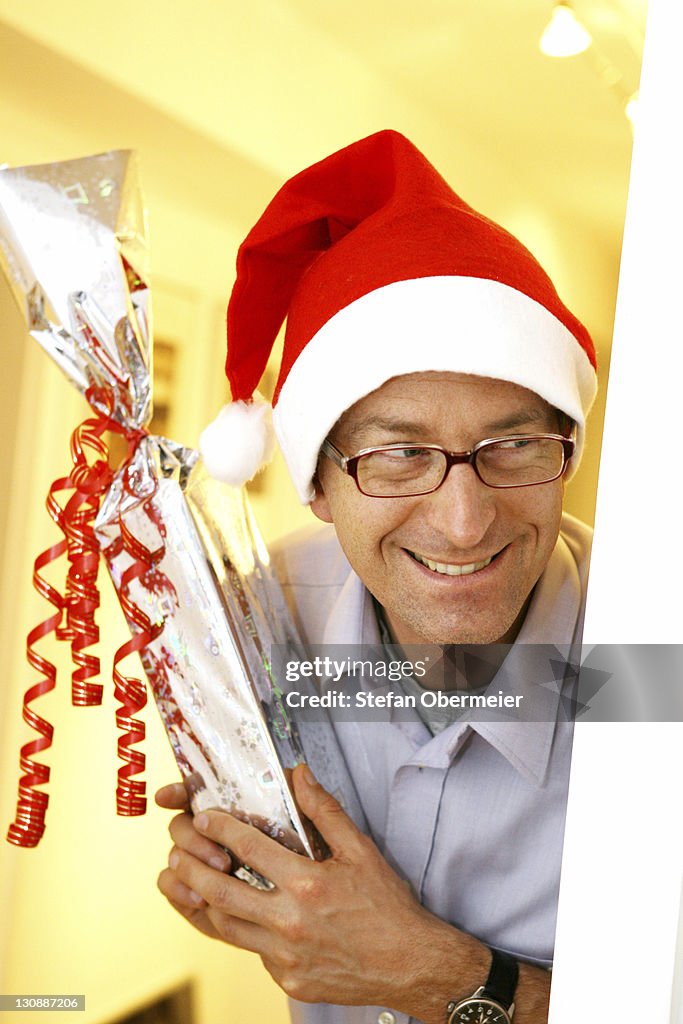 Man disguised as Santa Claus with a gift