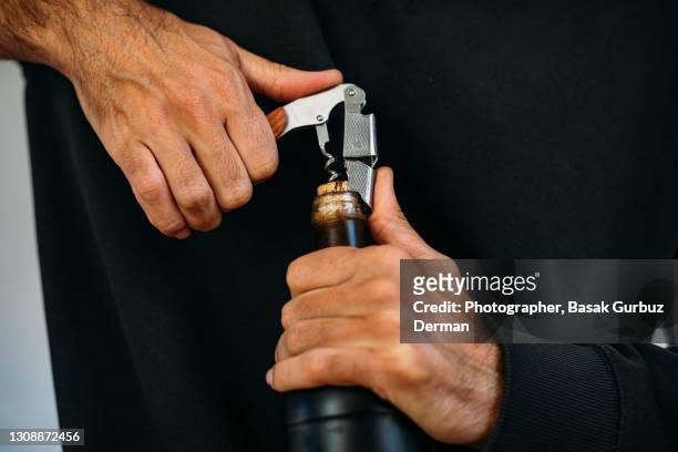 close-up of a man's hands opening a wine bottle with a corkscrew - corkscrew foto e immagini stock