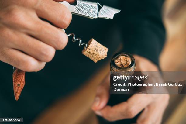 close-up of a man's hands opening a wine bottle with a corkscrew, and a broken wine cork - corkscrew foto e immagini stock
