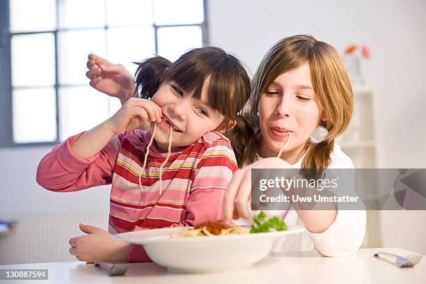 two girls eating spaghetti together - 10 11 years stock pictures, royalty-free photos & images