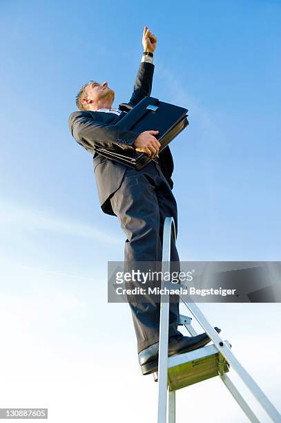 businessman climbing a ladder, symbolic image for the career ladder - low motivation stock pictures, royalty-free photos & images