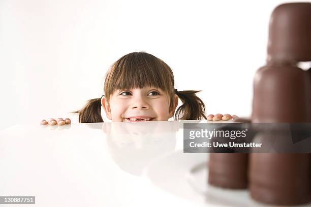 girl in front of a plate of chocolate marshmallows - in tischhöhe stock-fotos und bilder