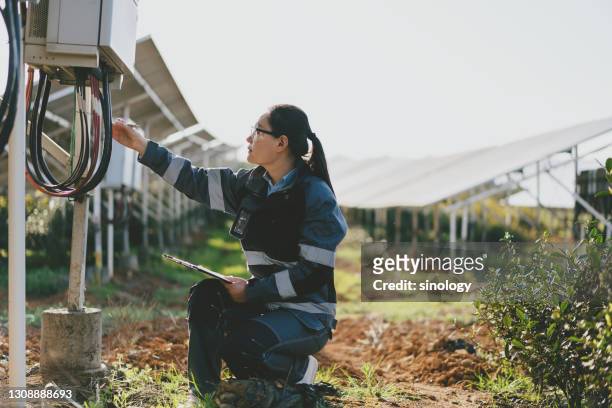 Asian female engineer working with laptop at solar power station during sunset