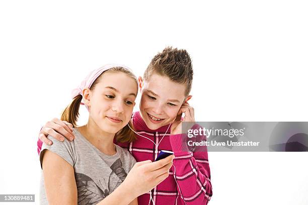 boy and girl listening to music together with headphones on an ipod - boy ipod bildbanksfoton och bilder