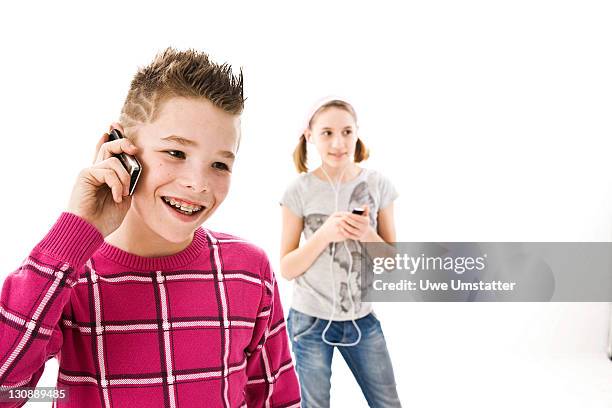 boy with a mobile phone and a girl with an ipod - boy ipod bildbanksfoton och bilder