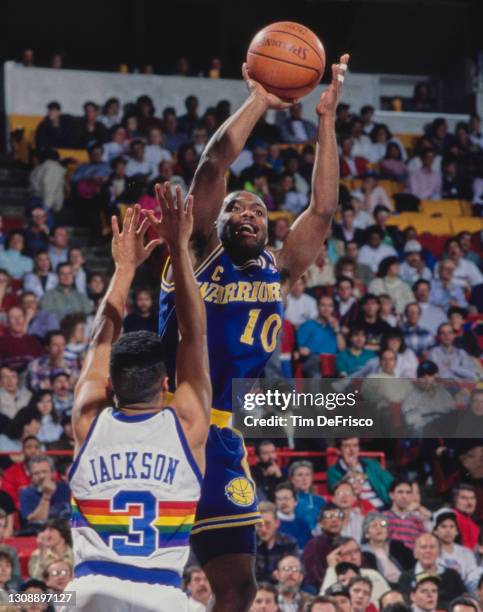 Tim Hardaway, Point Guard for the Golden State Warriors attempts a one handed shot to the basket as Chris Jacksonof the Denver Nuggets tries to block...