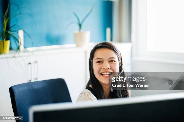office employee laughing while sitting at desk working - call center headset stock pictures, royalty-free photos & images
