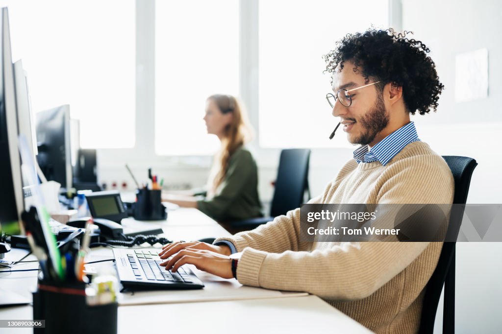 Man Working At Computer And Talking To Clients On Phone