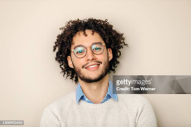 portrait of male office employee with curly hair smiling - one young man only fotografías e imágenes de stock