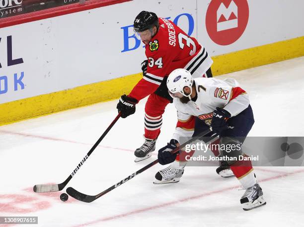 Carl Soderberg of the Chicago Blackhawks and Radko Gudas of the Florida Panthers battle for the puck at the United Center on March 23, 2021 in...