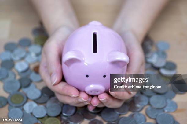 female ands holding pink piggy bank. - childrens health fund benefit stock-fotos und bilder