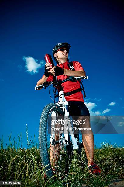 mountain biker taking a break, holding water bottle - athlete bulges stock pictures, royalty-free photos & images