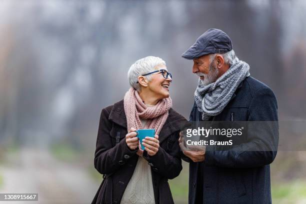 happy senior couple talking while having a drink in nature. - mature couple winter outdoors stock pictures, royalty-free photos & images