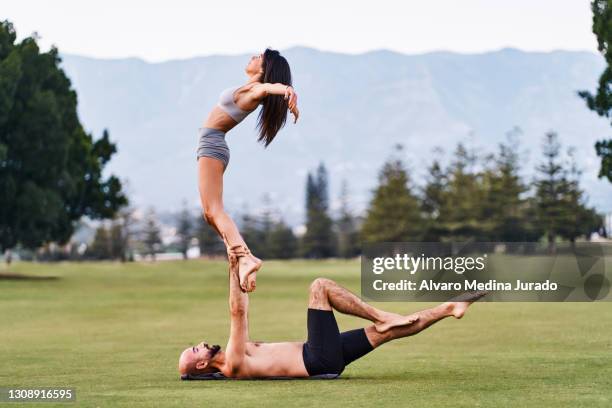 couple doing acro yoga together on meadow - yoga prop stock pictures, royalty-free photos & images