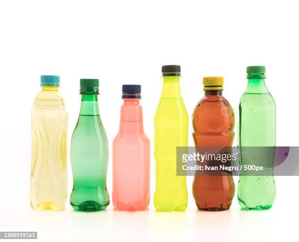 close-up of multi colored plastic bottles against white background - cola bottle photos et images de collection