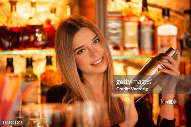 porträt einer glücklichen barkeeperin, die getränke an einer bar in einem cocktailmixer trinkt - bartender mixing drinks stock-fotos und bilder