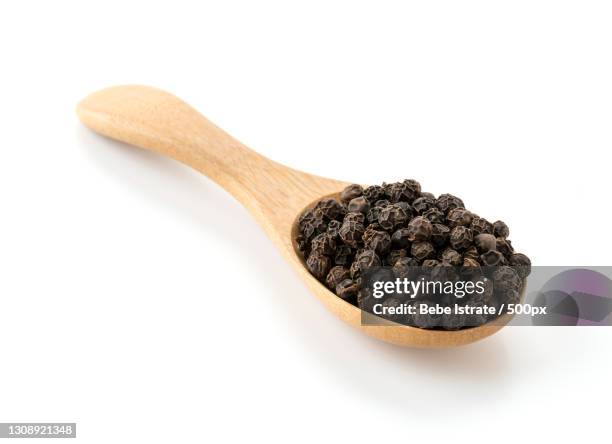 close-up of black peppercorns in spoon against white background - ペッパー ストックフォトと画像