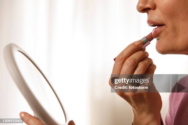 unrecognizable woman holding a mirror and applying lipstick - pale lipstick stock pictures, royalty-free photos & images