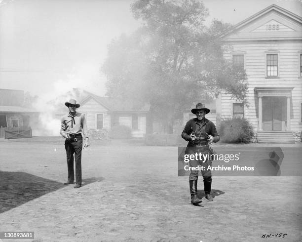 Lon Chaney Jr and unidentified man holding guns in a scene from the film 'High Noon', 1952.