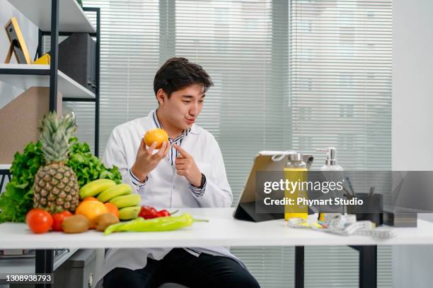 nutritionist uses a digital tablet to conduct an online consultation with his patient - nutritionist stock pictures, royalty-free photos & images