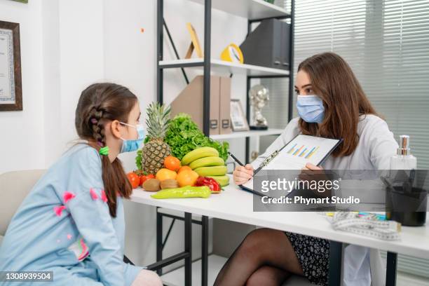 diététiste tenant le plan de régime pendant la consultation avec le patient d’enfant dans le bureau - système endocrinien photos et images de collection