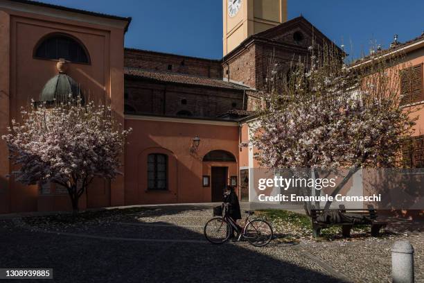Woman pulls her bicycle while speaking at the phone past the main town church on March 24, 2021 in Codogno, Italy. Codogno was Italy's first...