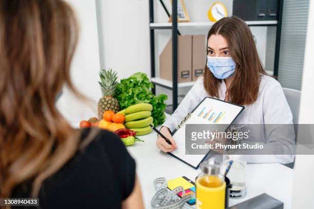 dietitian holding diet plan during consultation with patient in the office - coach stock pictures, royalty-free photos & images