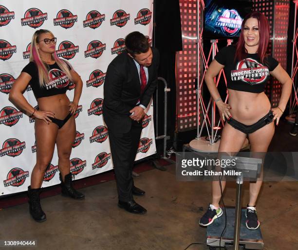 Lauren "The Animal" Fogle looks on as ring announcer and host A.J. Kirsch checks the scale as Sarah "The Beast" Brooke weighs in for their match...