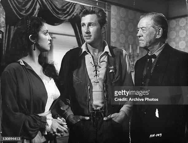 Lloyd Bridges and Tom London urge Katy Jurado to remain in Hadleyville in a scene from the film 'High Noon', 1952.