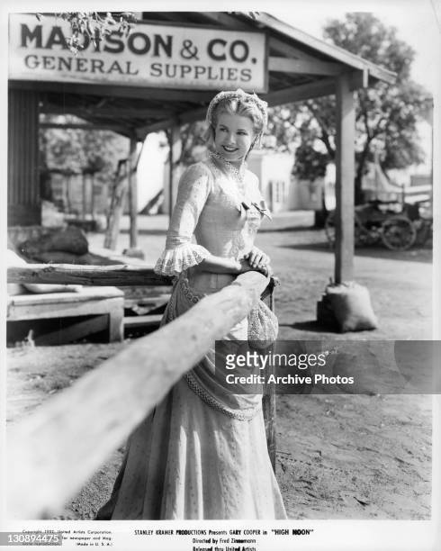 Grace Kelly smiling as she's leaning up against fence in a scene from the film 'High Noon', 1952.