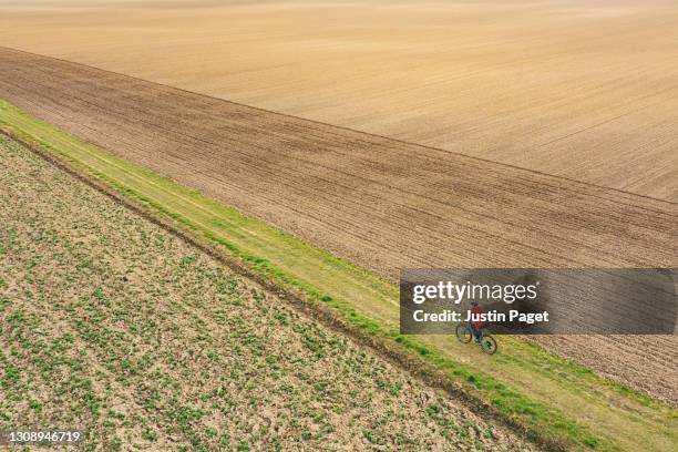 drone view of cyclist on rural track - drone images stock-fotos und bilder