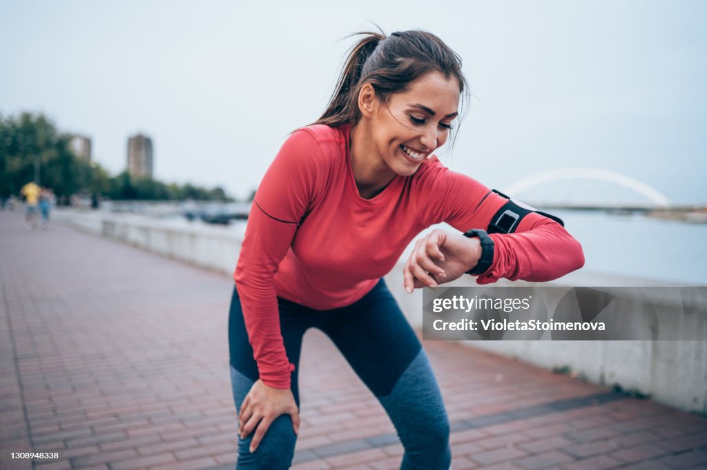 Joven deportiva revisando la hora después de trotar.