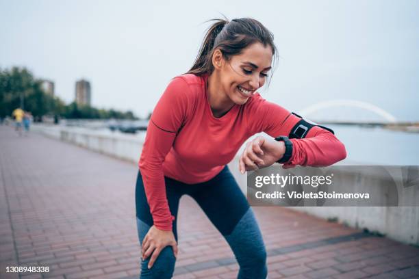 joven deportiva revisando la hora después de trotar. - women running fotografías e imágenes de stock