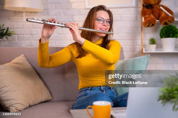 young woman in yellow pullover playing flute to people online. - flautist stock pictures, royalty-free photos & images