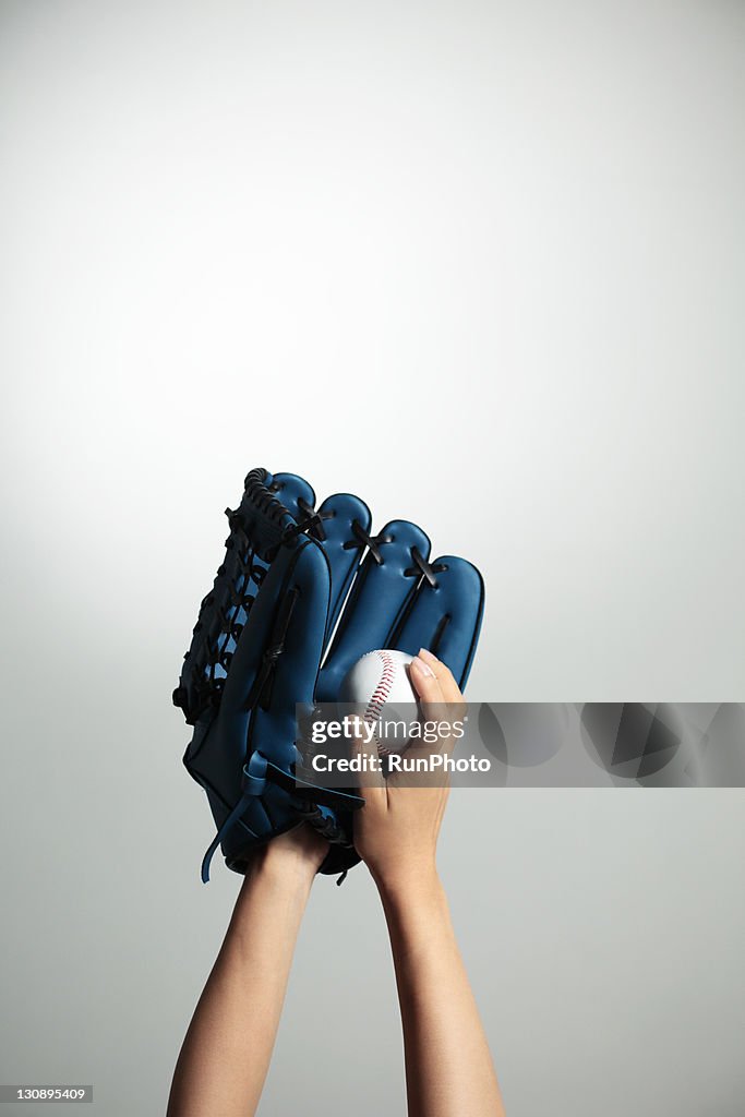Hand holding a baseball glove and ball