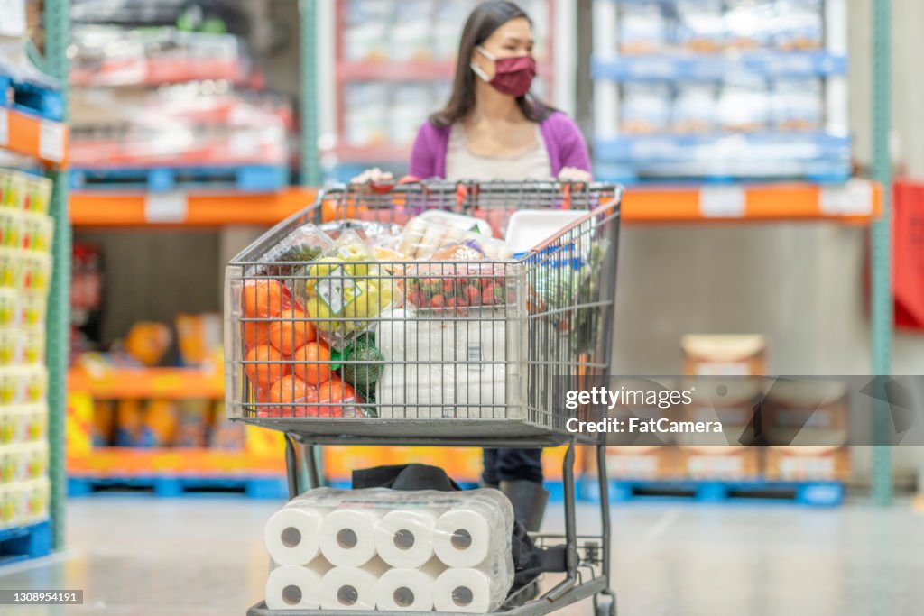 Asian Woman Pushing Shopping Cart Full Of Groceries