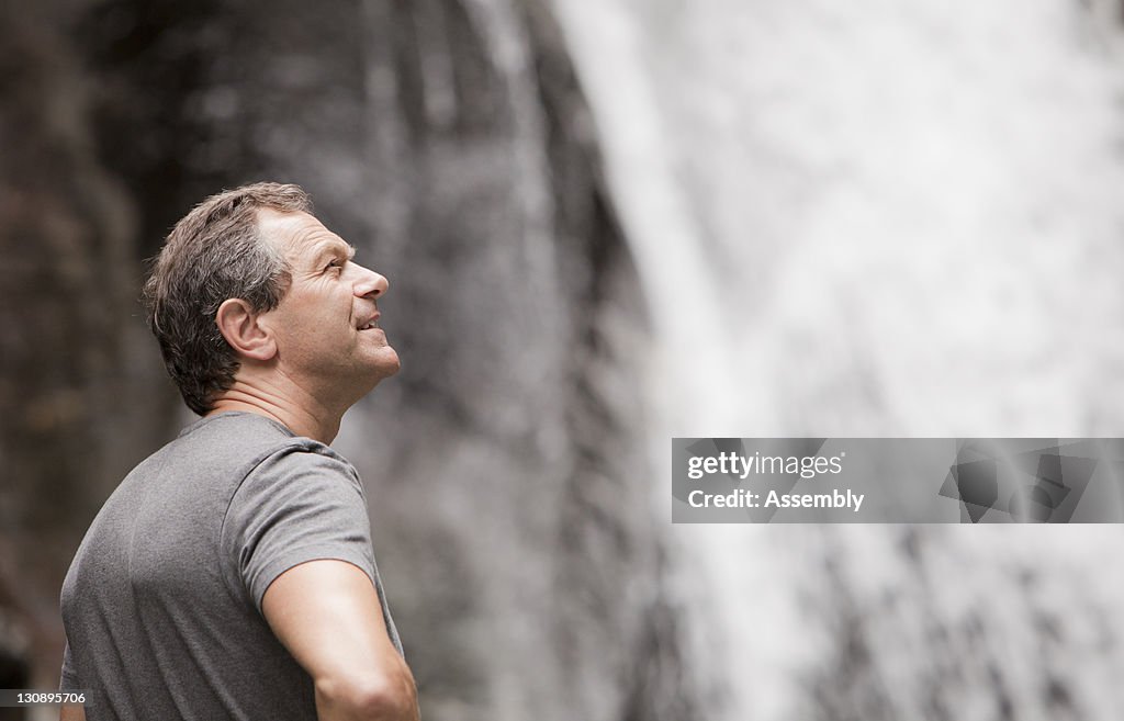 Man looks at a waterfall on a hike