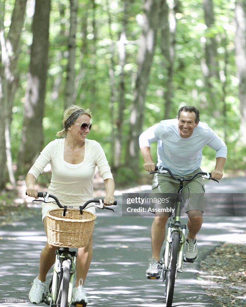 Couple rides bikes on tree lined path