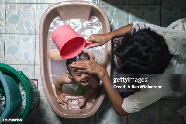 baby girl taking bath - babyface stock-fotos und bilder