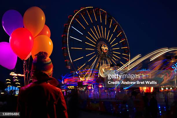 woman holding balloons overlooking fairground - kingston upon hull stock pictures, royalty-free photos & images