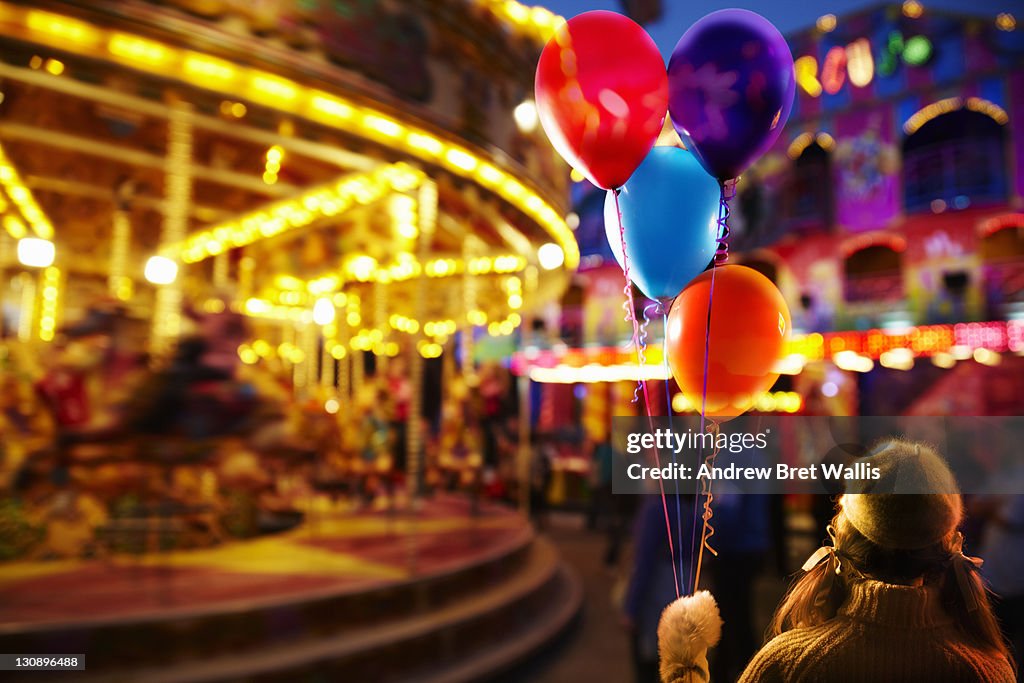 Young girl holding balloons at the fairground