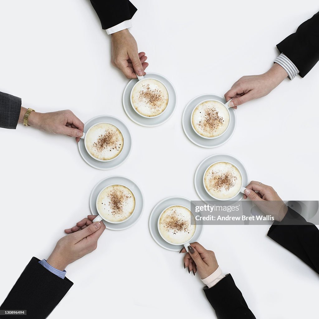 Circle of business colleagues holding coffee cups