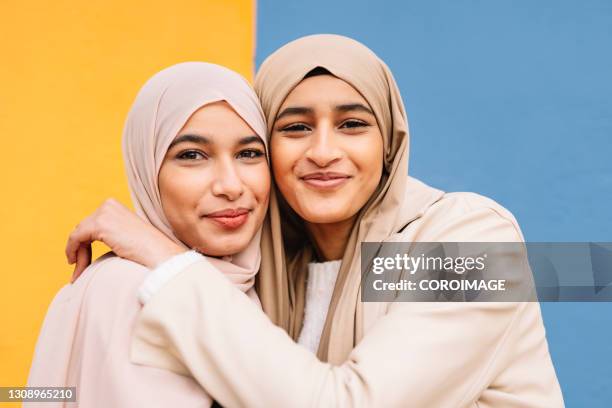 two arab female friends hugging each other outdoors. - emirati face smile fotografías e imágenes de stock