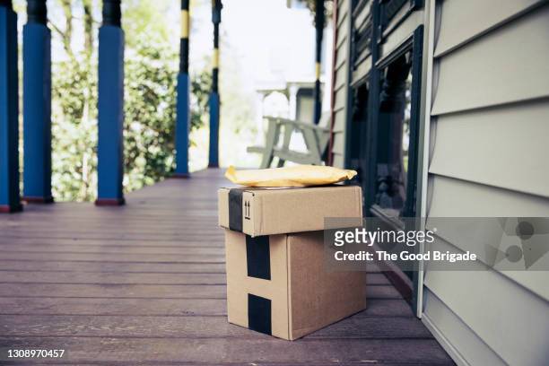stack of packages on front porch after mail delivery - delivering imagens e fotografias de stock