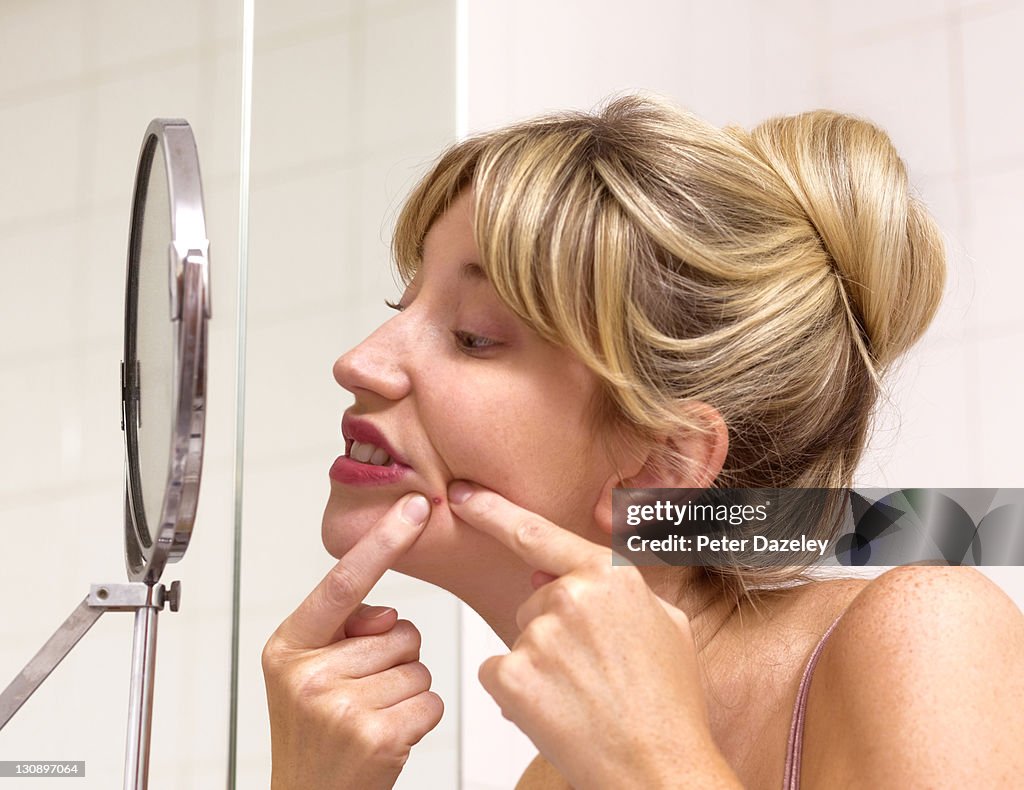 Girl squeezing zit in bathroom