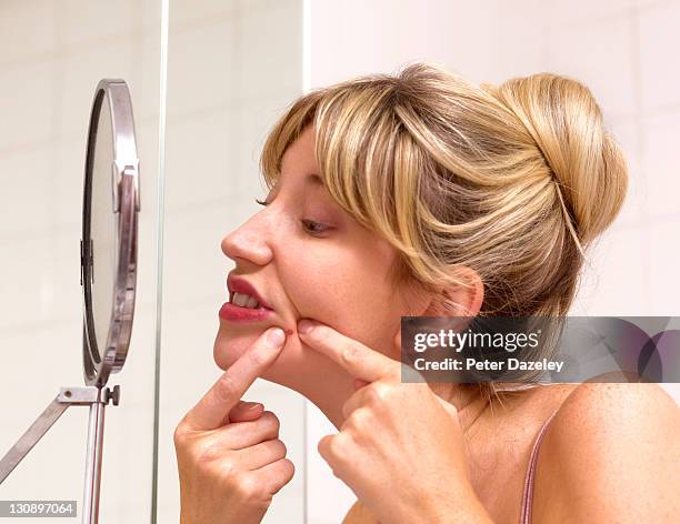 girl squeezing zit in bathroom - adult acne stock pictures, royalty-free photos & images