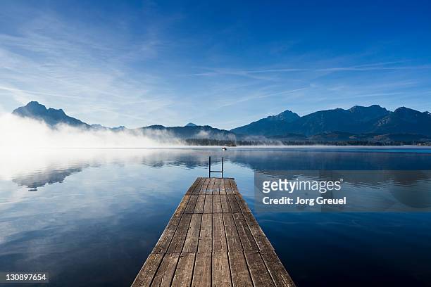 a wooden jetty on lake hopfensee at sunrise - lago foto e immagini stock